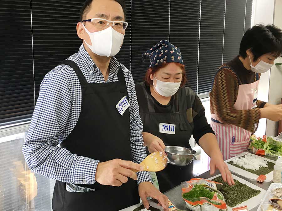 手助けを受けて料理する所長